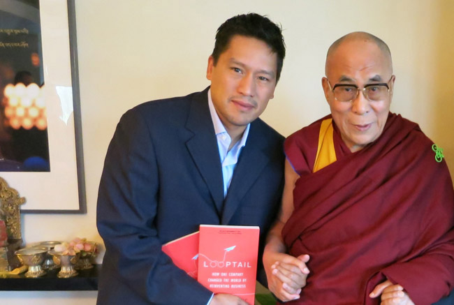 G Adventures founder Bruce Poon Tip shares an inspiring moment with His Holiness The Dalai Lama, during the publication of Bruce's New York Times Bestselling memoir, "Looptail" in 2013. (Photo credit: G Adventures, Inc.)