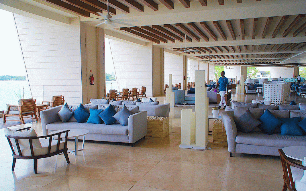 The lobby at Royalton Negril Resort & Spa brings beach vibes indoors with blue decor and water views.