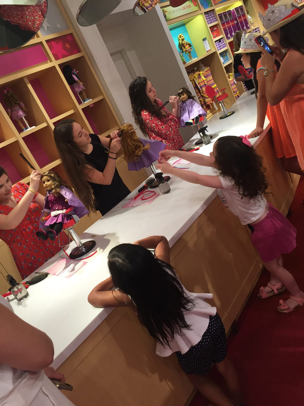 Moms and daughters watch as their dolls get a makeover at The American Girl doll store.