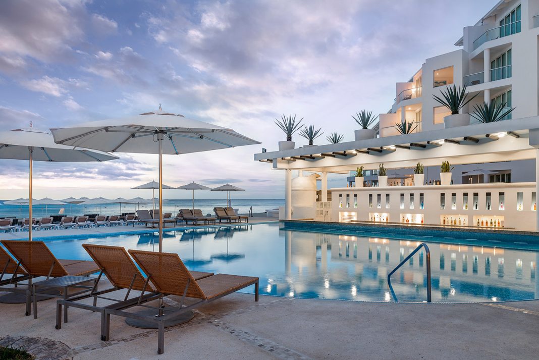 Guests at Playacar Palace can relax by the pool while looking out at the ocean.
